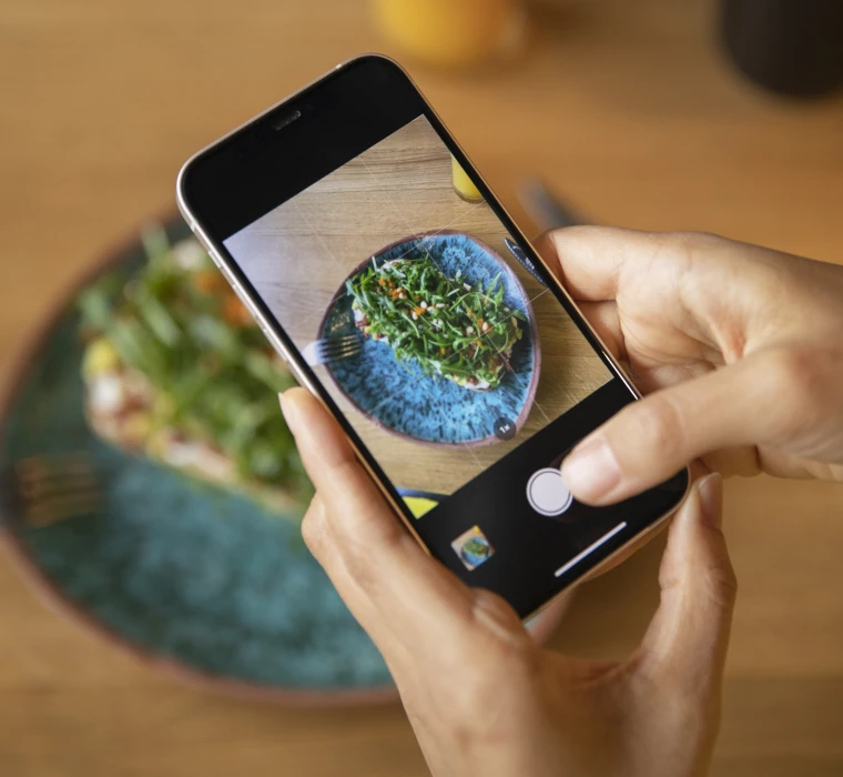 Tu lances ton entreprise : par où commencer pour te faire connaître ? Mains qui prennent une photo avec un smartphone